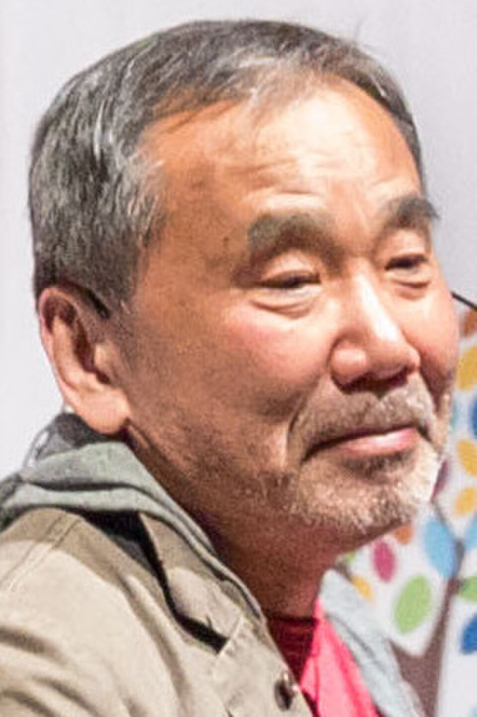 Retrato del novelista Haruki Murakami, con una leve sonrisa, cabello y barba canosos