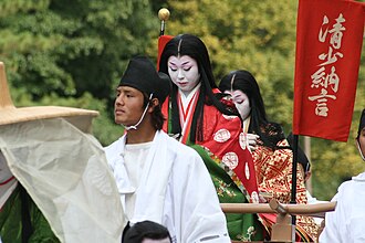 Participantes del Jidai Matsuri con atuendos de la corte Heian y un estandarte rojo con el nombre de Sei Shōnagon